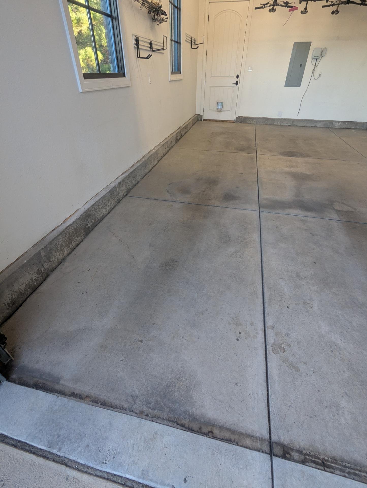 Stained gray concrete floor with saw-cut joints and wall base in a Colorado Springs 3+ car garage before polyaspartic coating