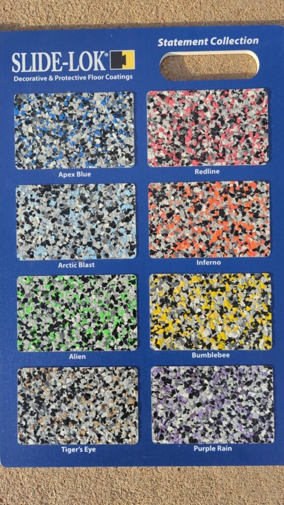 Slide-Lok Statement Collection flake sample board showing Apex Blue, Redline, Arctic Blast, Inferno, Alien, Bumblebee, Tiger's Eye, and Purple Rain garage floor blends